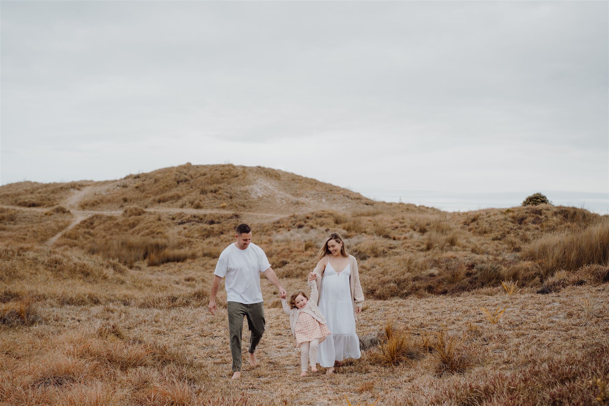 A family walking along papamoa beach during a family photoshoot by haley adele photography