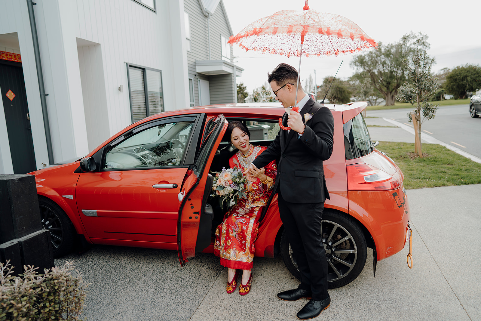 A groom being helped out of a car by the groom during a chinese tea ceremony in Auckland city while being photographed by wedding photographer Haley Adele Photography