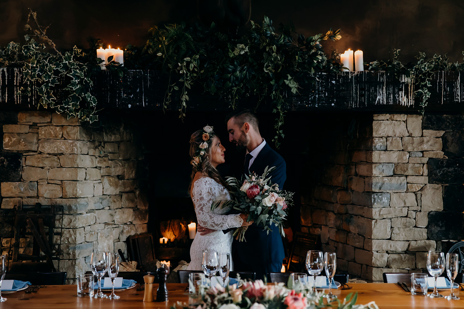 A bride and groom standing in front of the fire place in The Stables Matakana Reception building, being photographed by Haley Adele Photography