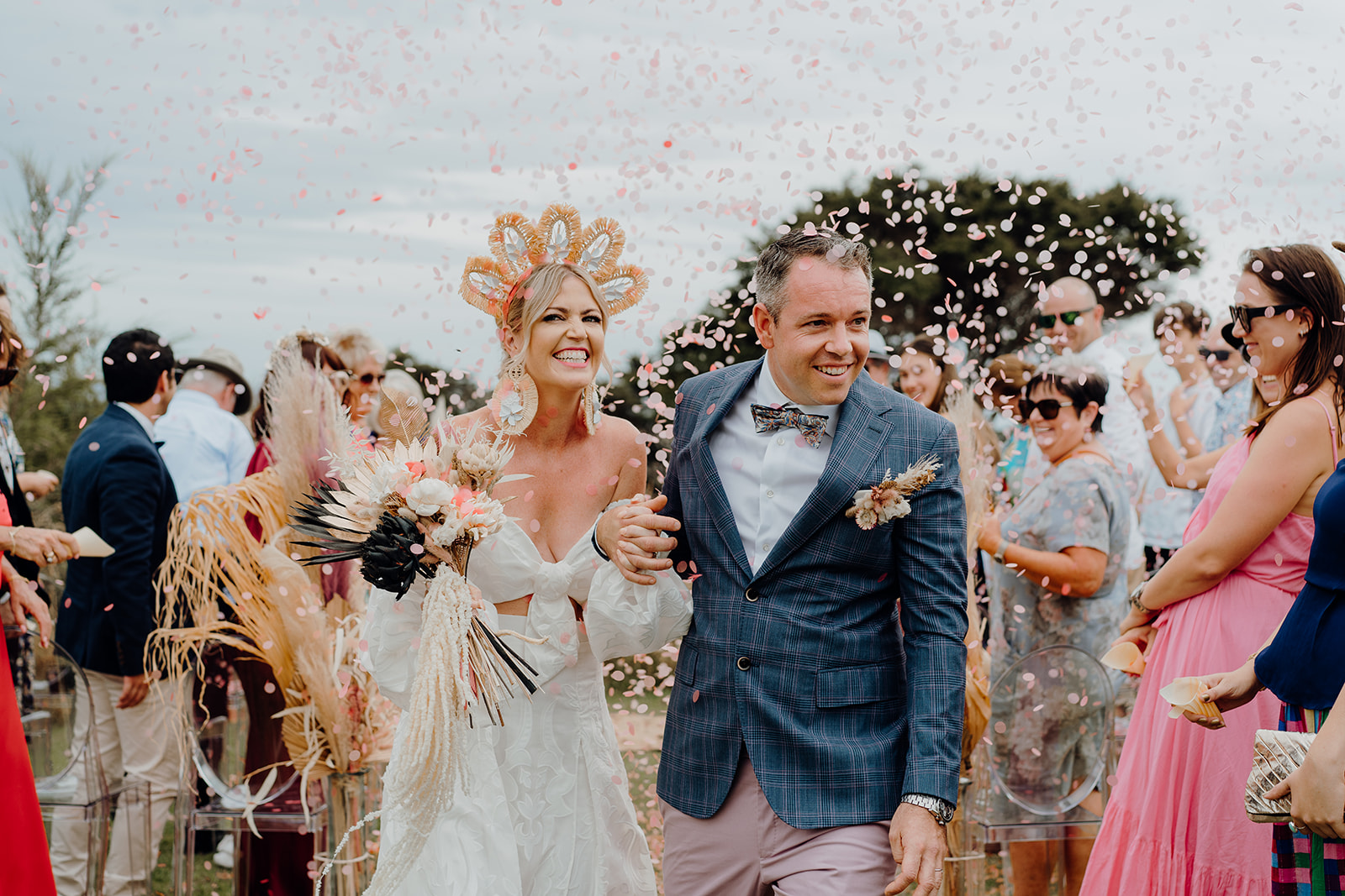 A bride and groom walking up the aisle while their guests through confetti on them and they're photographed by Waikato Photographer Haley Adele Photography