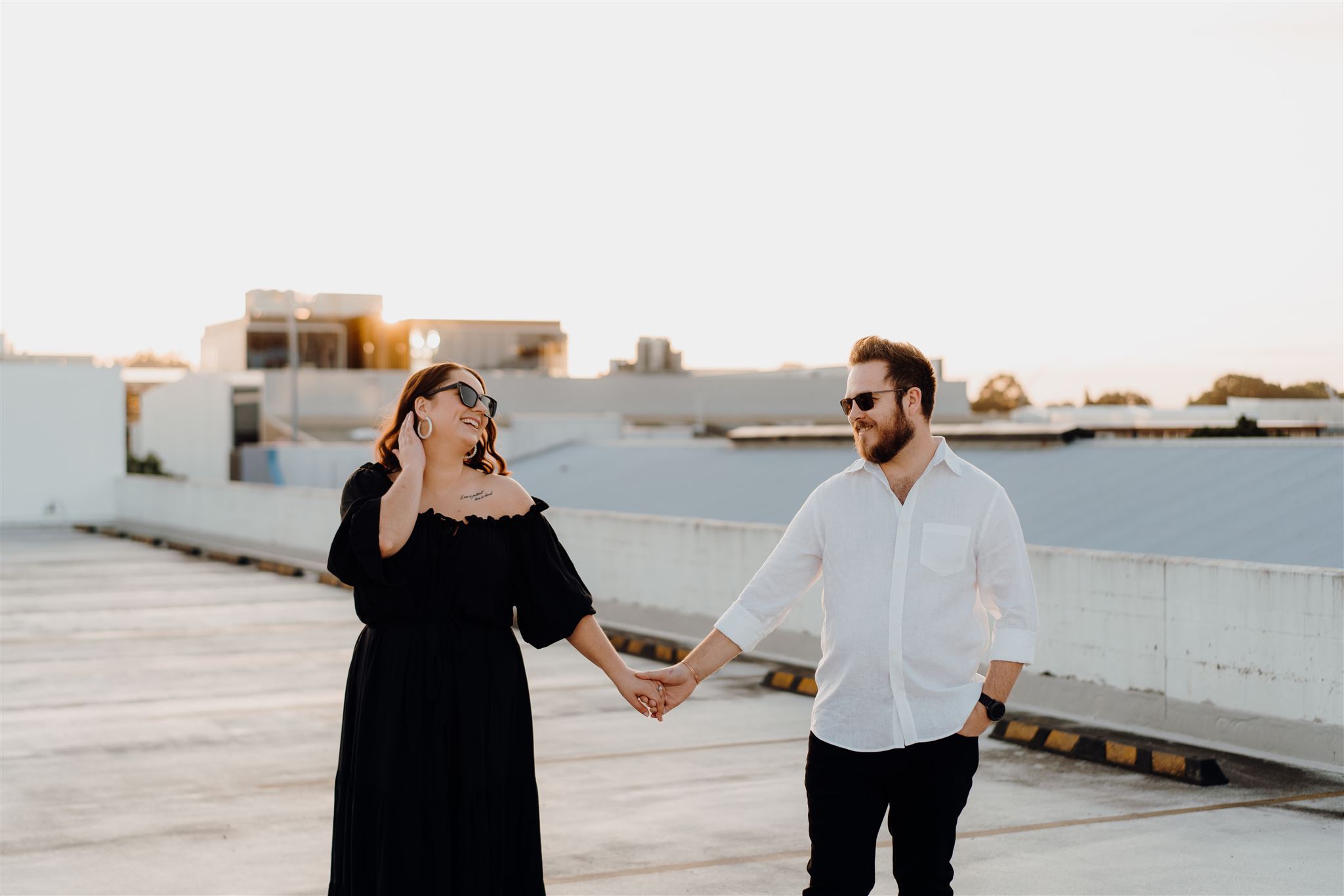 A couple standing on a rooftop in Hamilton city during an engagement photoshoot with Waikato Photographer Haley Adele Photography