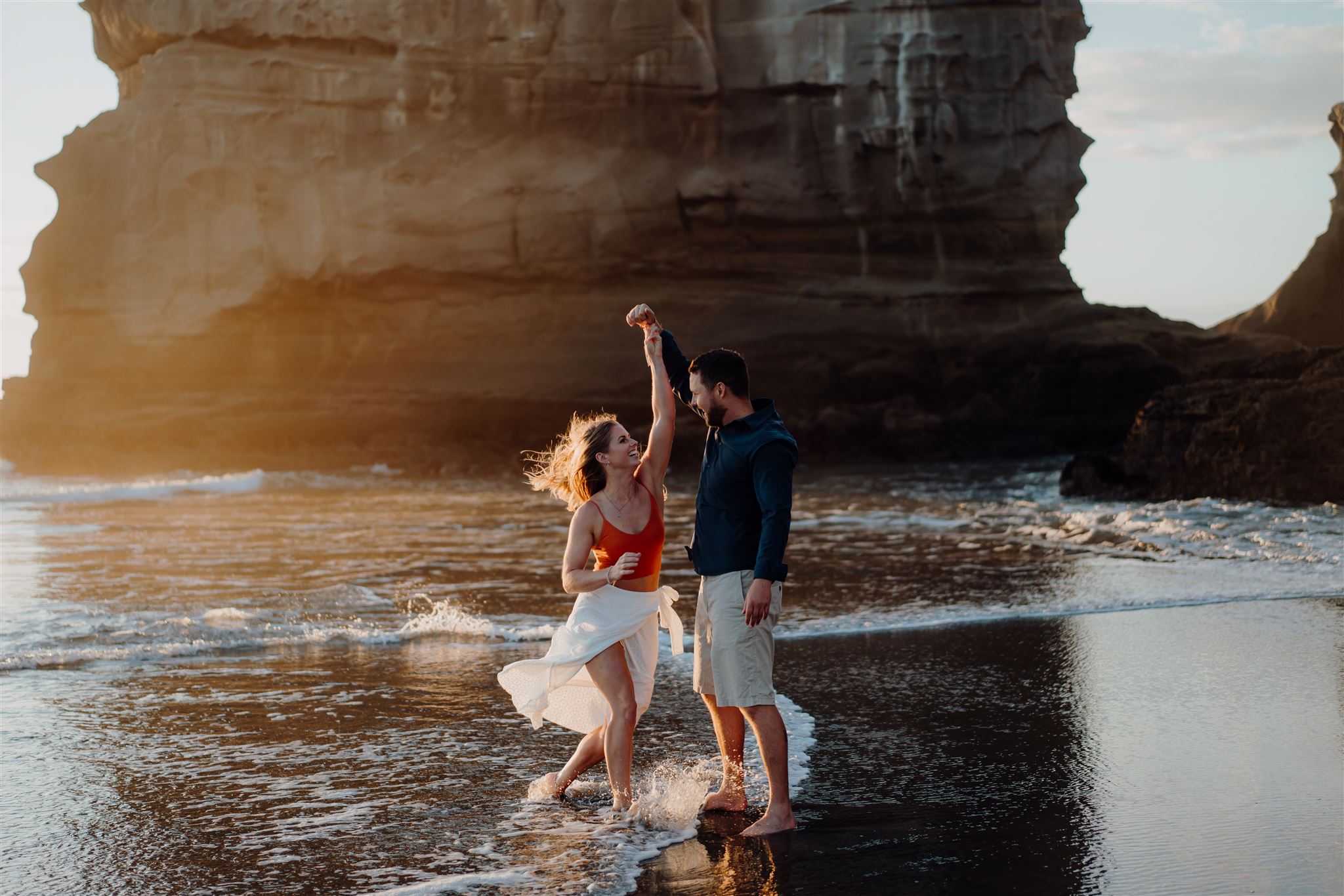 A couple dancing on the beach during an engagement photoshoot at Muriwai by the Gannet Colony Cliffs, photographed by wedding photographer haley adele photography