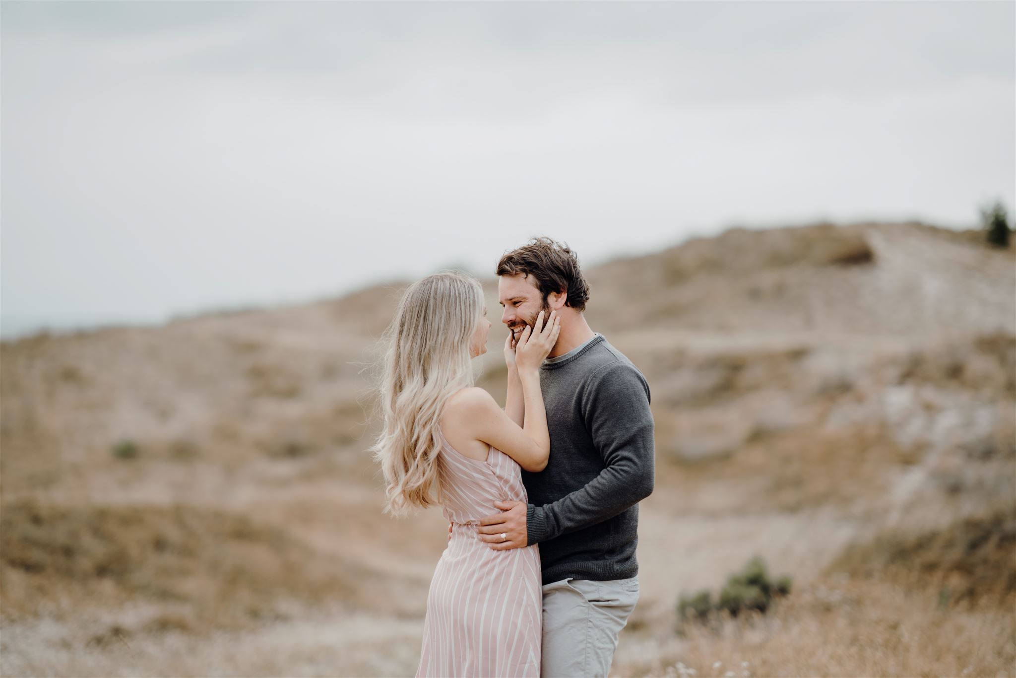 A couple embracing each other at Papamoa Beach while being photographed during a couple photoshoot by Waikato Photographer Haley Adele Photography