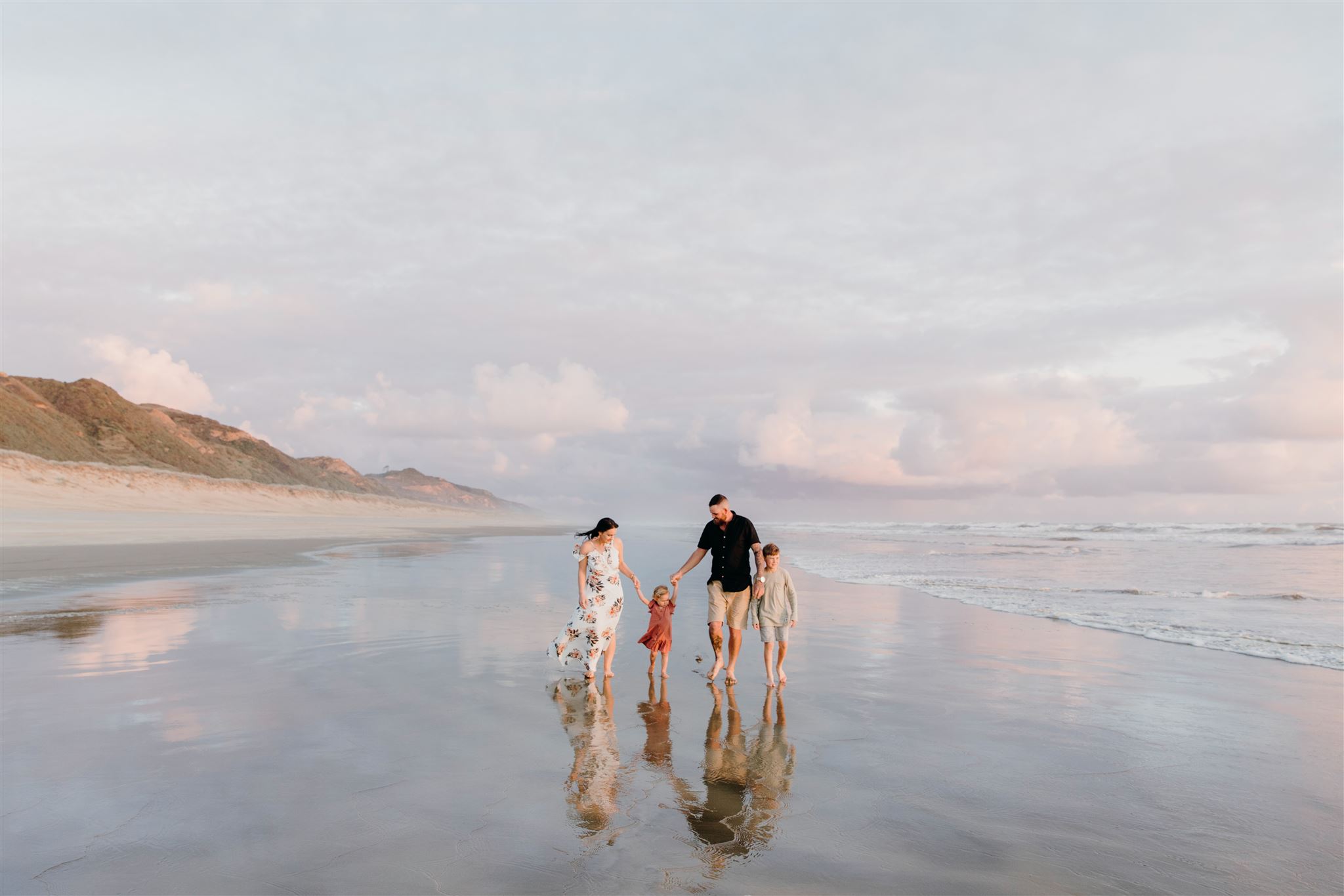 A family walking down a beach holding hands in Dargaville, Northland during a family photoshoot by Waikato Photographer Haley Adele Photography