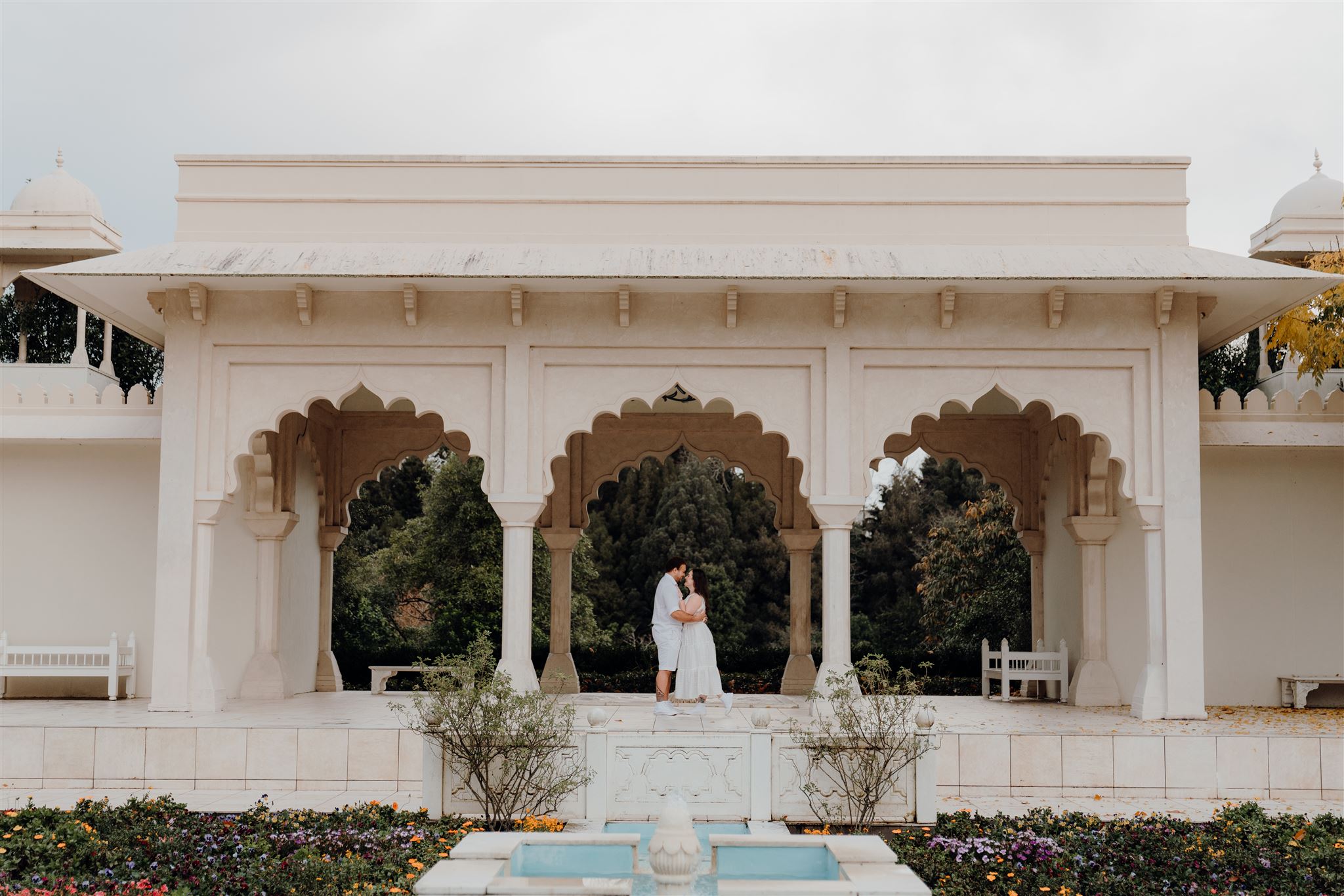 A couple wearing white holding one another in the Indian Garden in the Hamilton enclosed gardens during a pre-wedding engagement photoshoot with photographer Haley Adele Photography