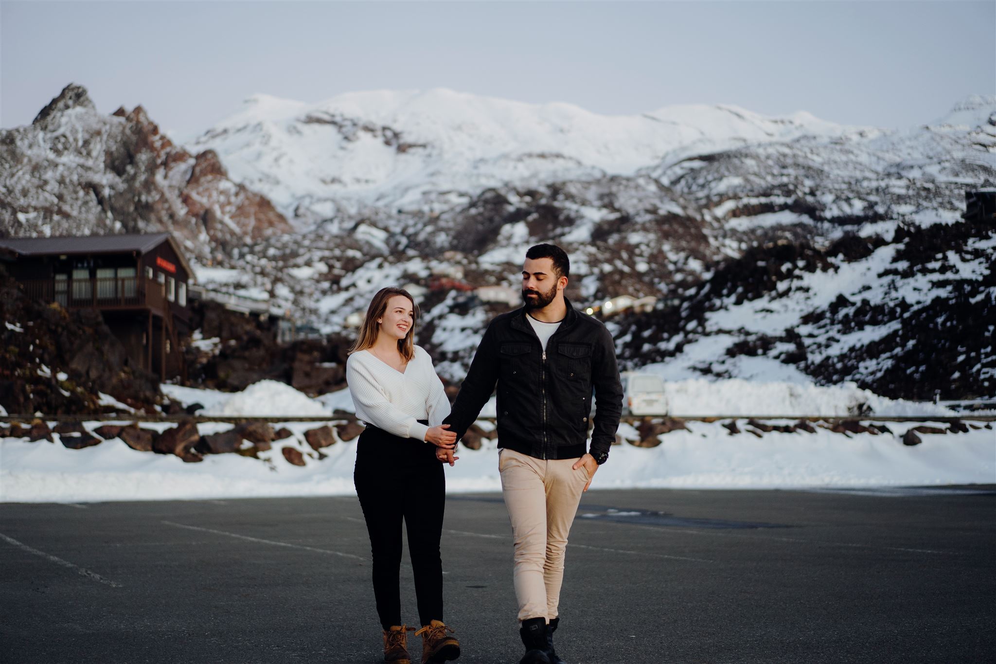 A couple walking in the car park at Mount Ruapehu Ski Fields photographed while on Holiday by wedding photographer Haley Adele Photography