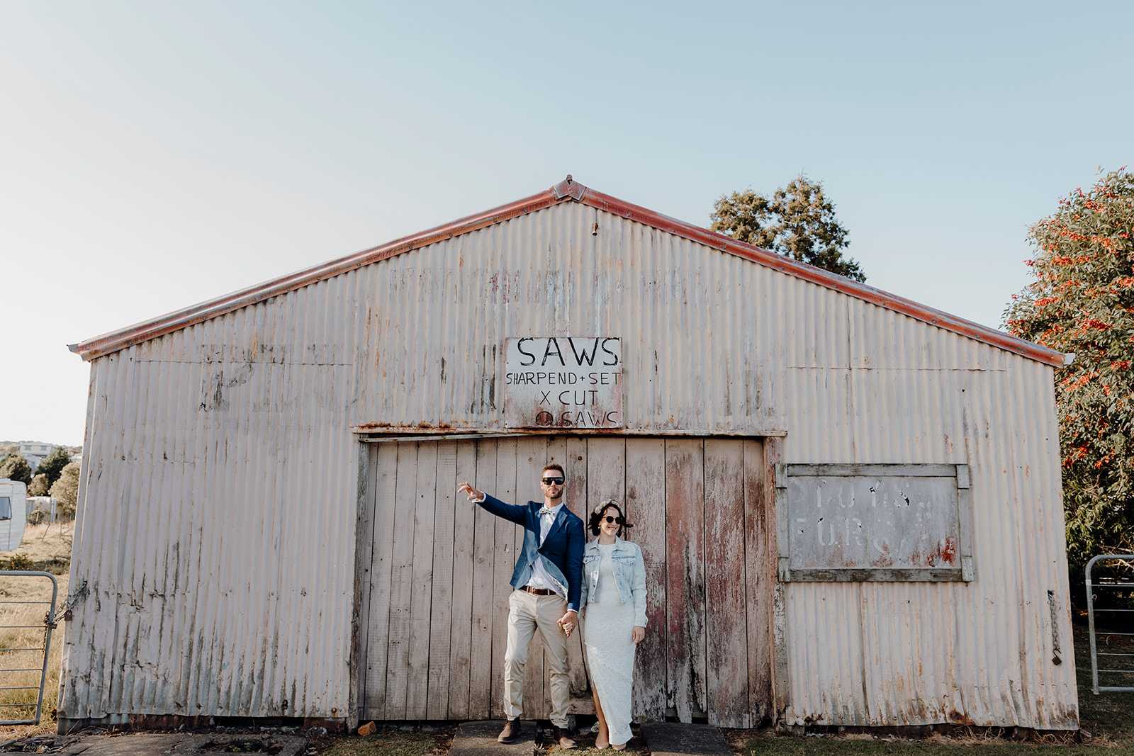 A bride and groom standing outside of the SAW rustic building in Mangawhai during their wedding photoshoot with Haley Adele Photography