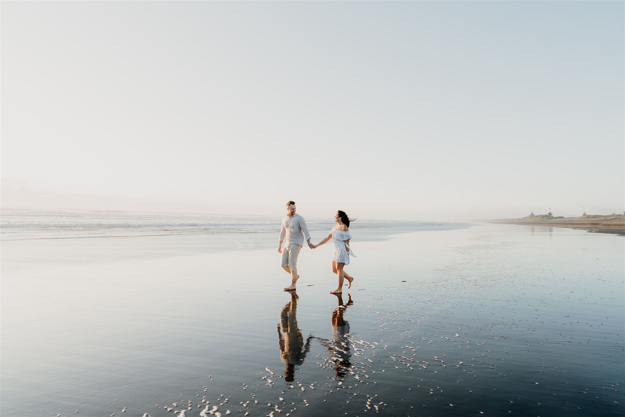 Muriwai Engagement Shoot Photograph of a couple walking along the beach