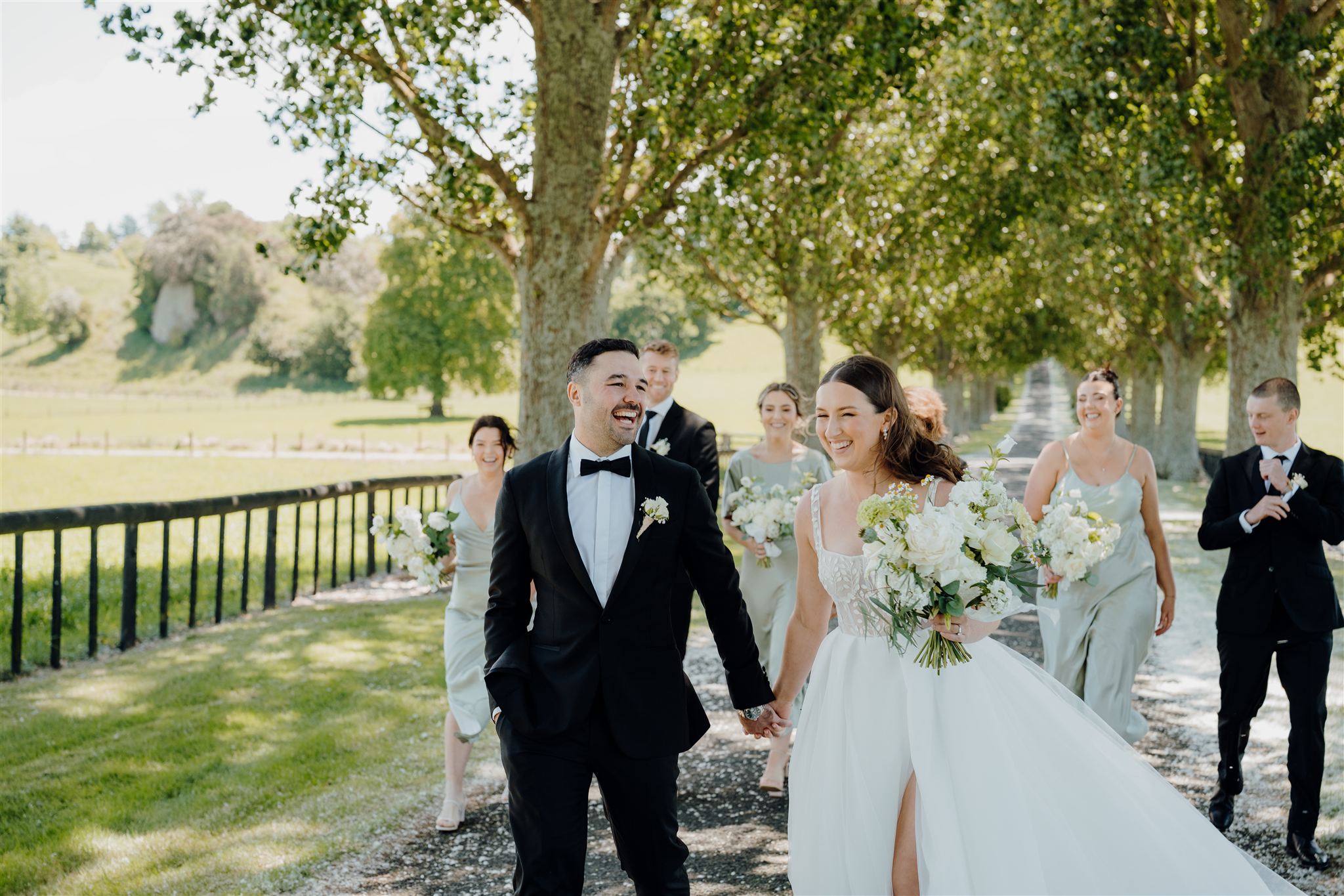 estelle and marinus who have just gotten married are walking down the driveway at the red barn in waikato during their photoshoot with their photographer haley adele photogaphy